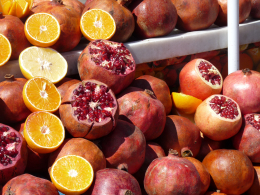 Granatapfel Hälftige Granatäpfel und Orangen auf einem Marktstand, leuchtende Farben.